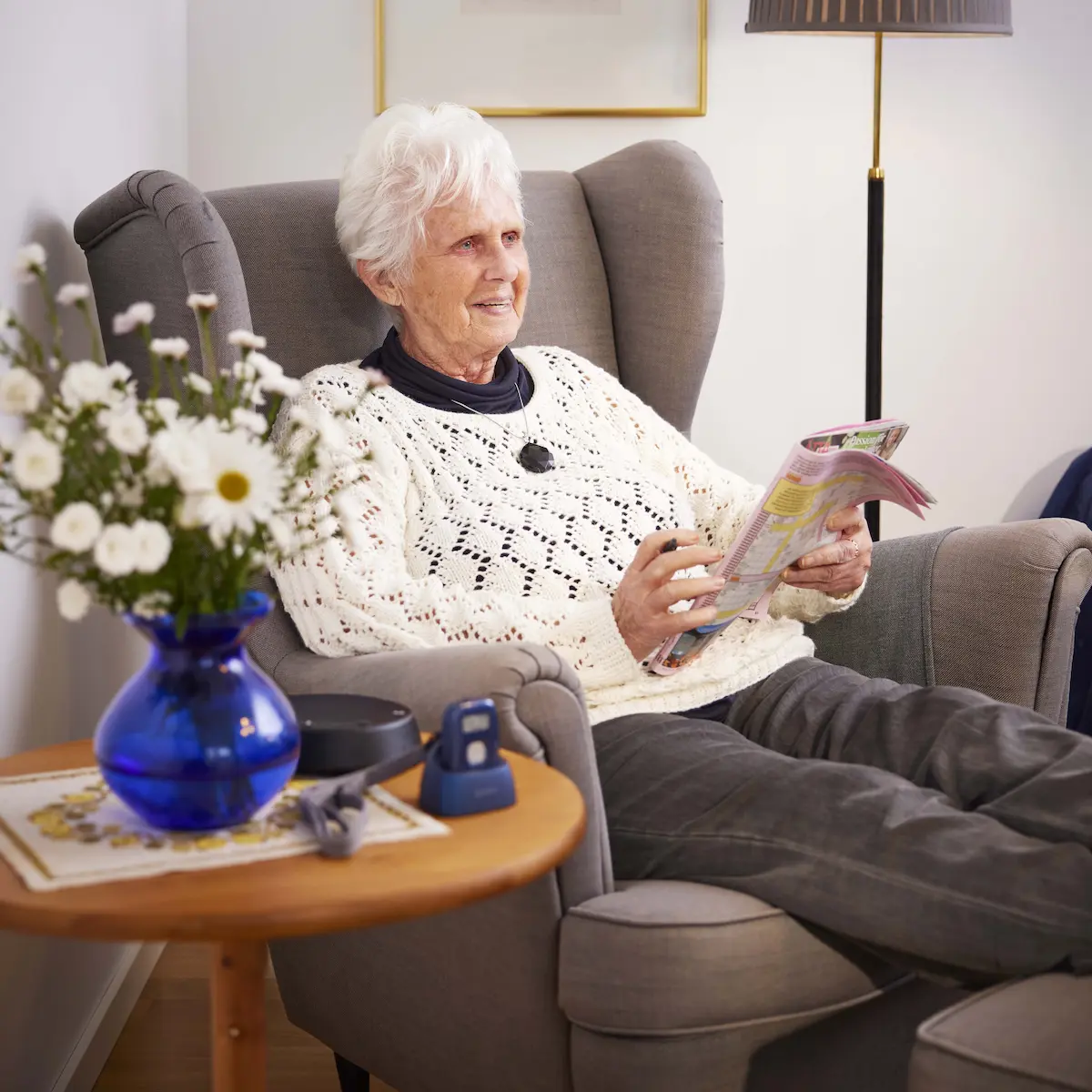 Collier alarmketting gedragen door oudere dame in huis met GPS tracker in de oplader