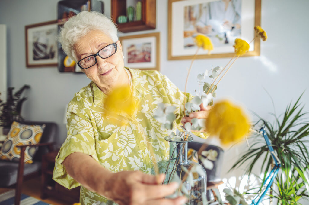 Persoonsalarmering van CSI vrouw doet gele bloemen in een vaas