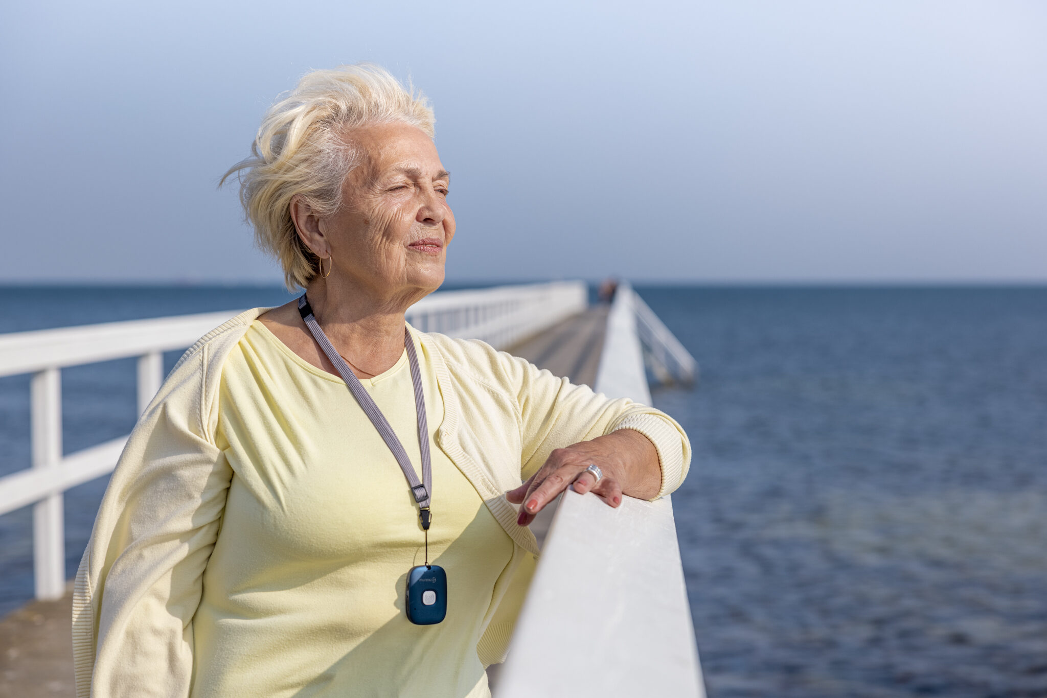 Persoonsalarmering van CSI oudere vrouw op een pier aan de zee met de Abby zender om haar nek.