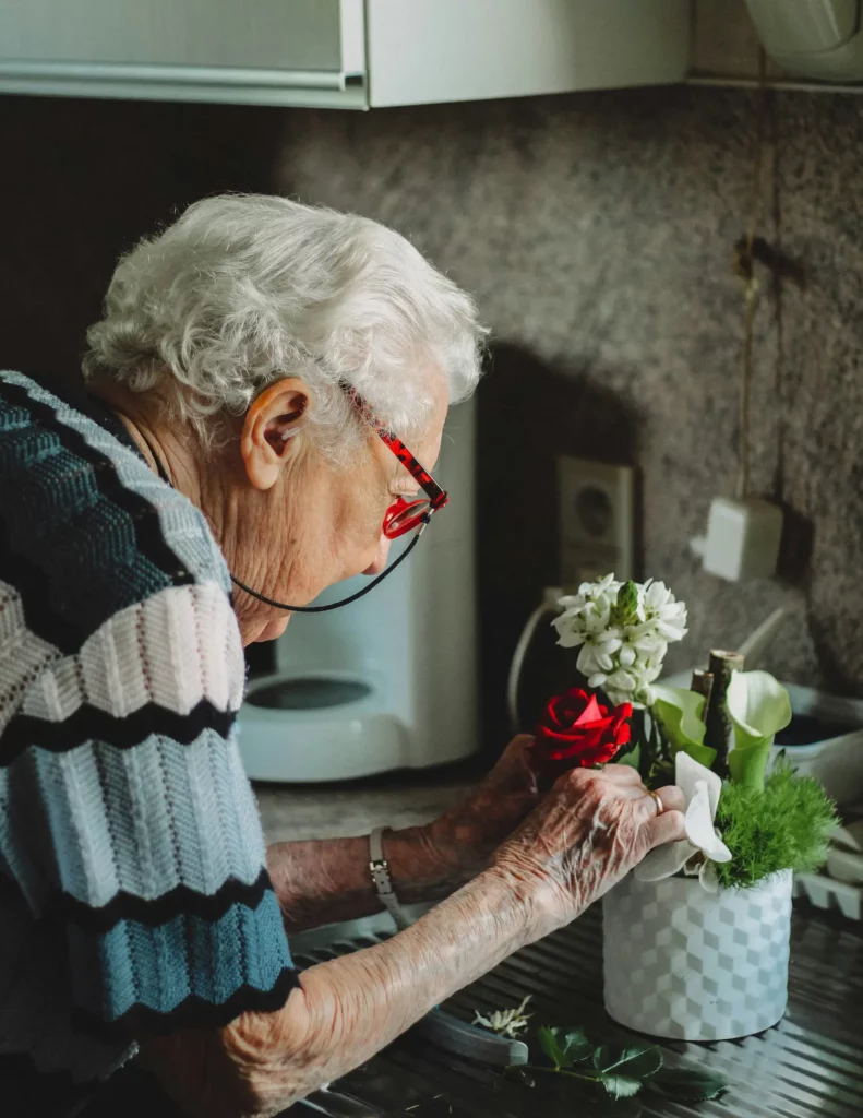 Oudere schikt bloemen in de keuken thuis