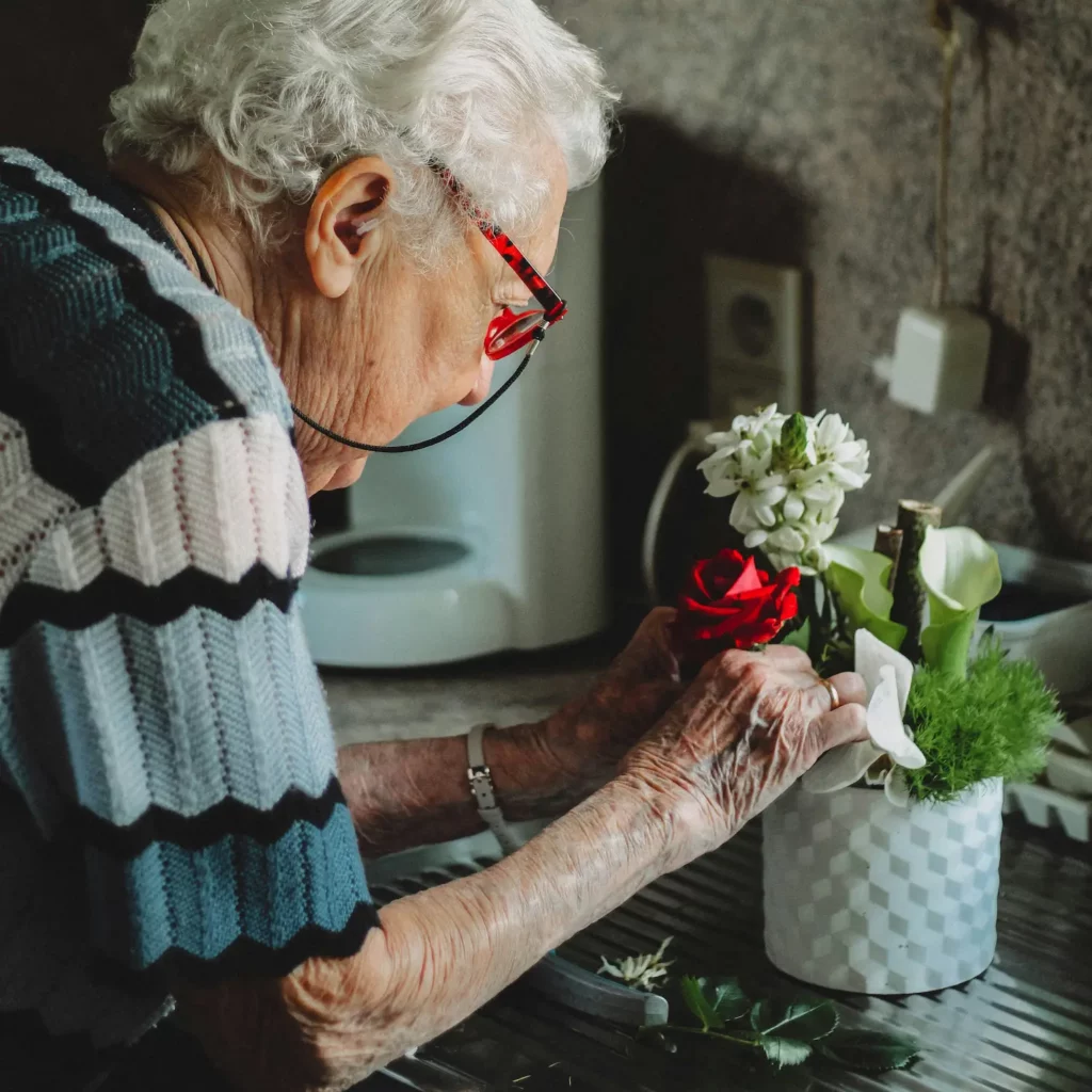 Oudere schikt bloemen in de keuken thuis