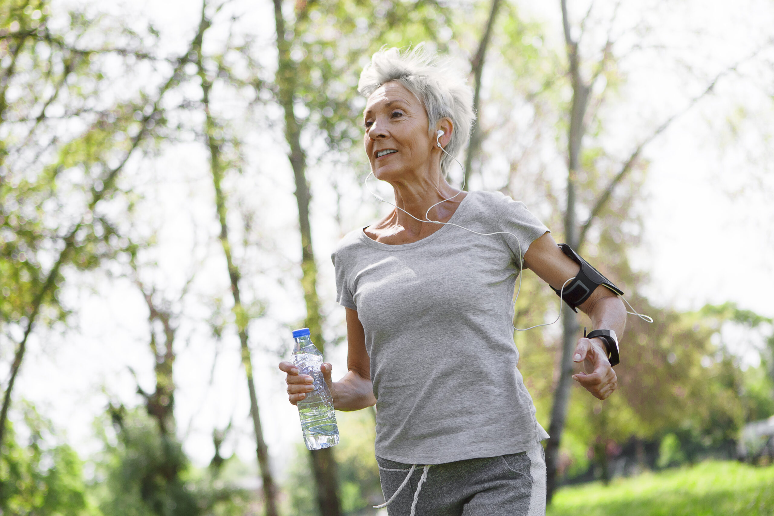 Oudere vrouw aan het hardlopen met technologie om de arm